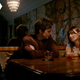 a man and woman sit at a table having drinks.